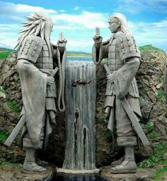 two statues are standing next to a waterfall