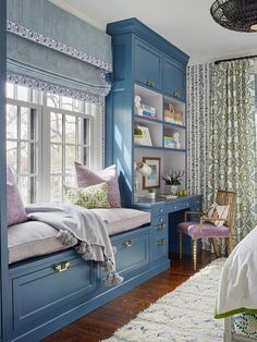 a bedroom with blue cabinets and window seat in the corner, along with a rug on the floor