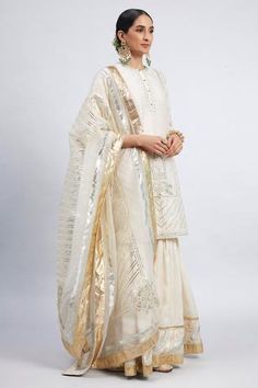 Daisy ivory kurta with gota trims and ghunghroo embellished placket. Comes with gharara and embroidered dupatta.
Component: 3
Embroidered
Neckline: Round
Sleeve Length: Three Quarter
Fabric: Kurta and Garara: Chanderi Silk; Dupatta: Silk Organza
Color: White
Side slits
Concealed placket - Aza Fashions Sheetal Batra, Chikankari Lehenga, Heavy Dresses, Geometric Fashion, Designer Kurti Patterns, Bridal Mehendi Designs, White Kurta, Lehenga Skirt, Embroidered Dupatta