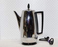 a silver tea pot sitting on top of a table next to a pair of scissors