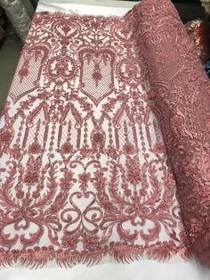 pink and white lace fabric on display at a store