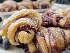 blueberry croissants with powdered sugar on top and berries in the background