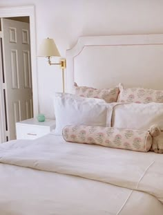 a bed with white sheets and pillows in a bedroom