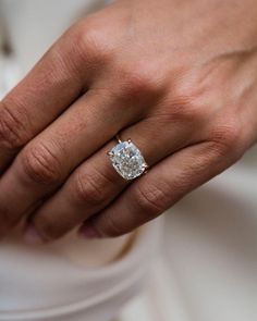 a close up of a person's hand with a diamond ring on their finger