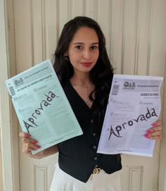 a woman holding up two different types of paper