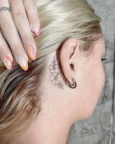 a woman with a flower tattoo on her left side behind the ear, looking down