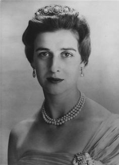 an old black and white photo of a woman in a dress with pearls on her neck