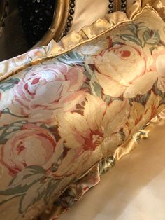 a close up of a flowered pillow on a bed with beaded trim around the edges