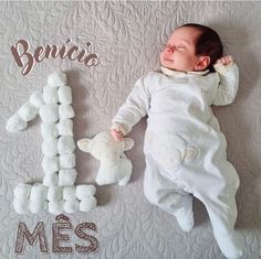 a baby laying on top of a bed next to a teddy bear and the words benio's mes written in spanish