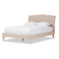 an upholstered bed with white sheets and pillows