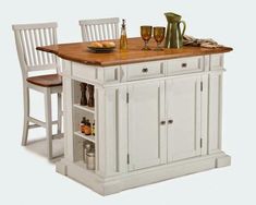 a white kitchen island with two chairs and a wooden counter top in front of it