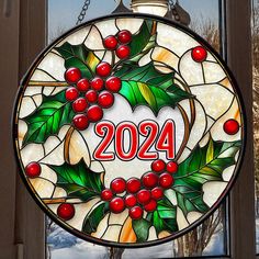 a round stained glass window with holly wreath and the number 2054 written in red