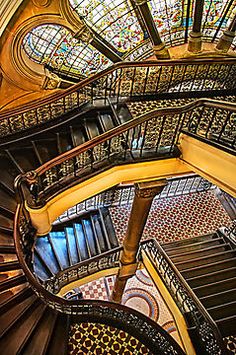 a spiral staircase with stained glass windows in the background