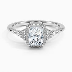 an engagement ring with a princess cut diamond and pave diamonds on the sides, in white gold