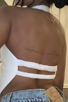 the back of a woman's white top with writing on her left shoulder and chest