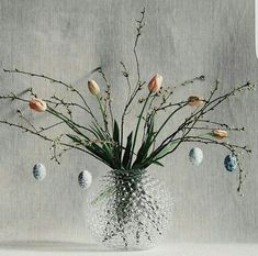 a vase filled with lots of flowers sitting on top of a white table next to a gray wall