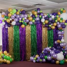 an arrangement of balloons and streamers in purple, green, gold and white colors