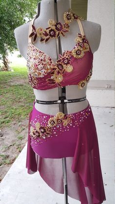 a mannequin wearing a purple dress with gold and red flowers on the bottom