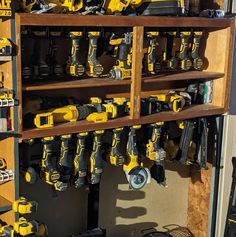 a shelf filled with lots of yellow and black power drillers on top of wooden shelves