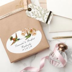 a package with a bird on it next to a pink ribbon and some other items