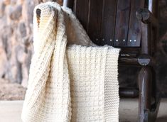 a white blanket sitting on top of a wooden chair