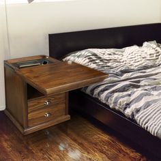 a bed sitting next to a wooden table on top of a hard wood floor