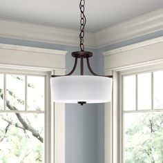 a light fixture hanging from a ceiling in a room with two windows and blue walls