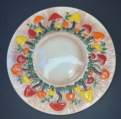 a white plate with colorful fruit and vegetables on the rim, sitting on a black surface