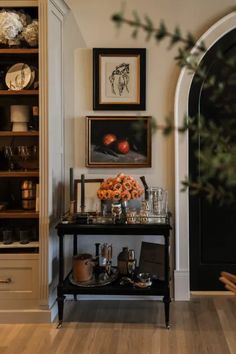 an entry way with shelves and pictures on the wall next to a vase filled with flowers