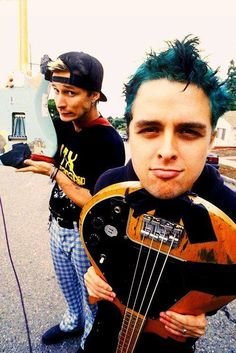 two young men with green hair are holding guitars