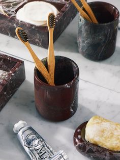 three toothbrushes are sitting in a cup next to some other items on a table