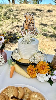 there is a cake and cookies on the table next to each other with a teddy bear topper