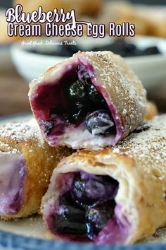 blueberry cream cheese - egg rolls are stacked on top of each other with powdered sugar