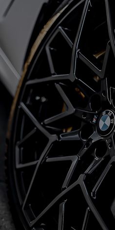 the front wheel of a white car with black spokes and gold accents on it