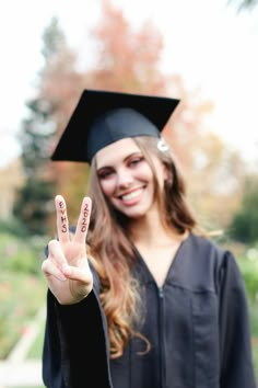 a woman in a graduation cap and gown making the peace sign