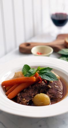 a white plate topped with meat and veggies on top of a marble counter