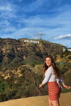 a woman standing in front of the hollywood sign