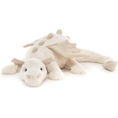 a white stuffed dragon laying on the ground