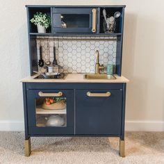 a blue kitchen cabinet with gold handles and knobs on the doors is open to reveal a sink