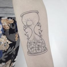 a woman's arm with a tattoo that has an hourglass and flowers on it