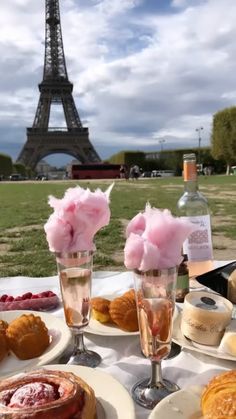 the table is set with desserts and pastries in front of the eiffel tower