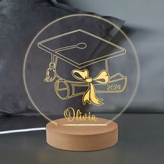 a graduation cap and tassel on top of a clear acrylic with gold lettering