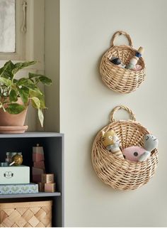 two wicker baskets are hanging on the wall next to a shelf with books and plants