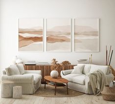 a living room with three paintings on the wall and two couches in front of them