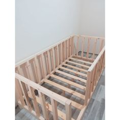 an unfinished bed frame in the corner of a room with wood flooring and white walls