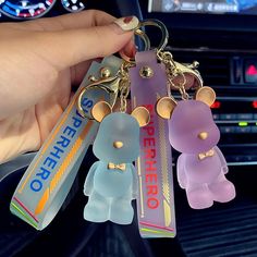 a person is holding two key chains in their hand while they are sitting in the car