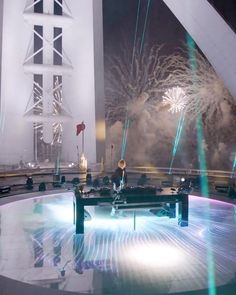 fireworks are lit up in the night sky over a stage with people sitting on it