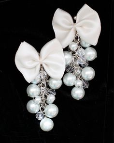 "Finish-off a whimsical ensemble with a pair of feminine and chic pearl and bow dangle earrings!! These stunning earrings feature darling satin bows, hand-sewn together, and finished with a cascade of glass pearls and crystal beads...An instant dose of style!! Cute enough for day; fancy enough for bridal!! Wouldn't this item make a lovely bridesmaid accessory?! ♥Brass base metal. ♥Choose from gold or silver. ♥Glass pearls. ♥Available in: Aqua, Black, White, Ivory (shown), or Pink. ♥Satin bows. ♥ White Bow Earrings For Wedding, White Bow Jewelry For Evening, White Pearl Earrings With Bow For Wedding, White Jewelry With Decorative Bow For Evening, White Evening Jewelry With Decorative Bow, Elegant Wedding Earrings With Ribbon, Elegant Ribbon Earrings For Wedding, White Pearl Earrings With Bow For Party, White Jewelry With Decorative Bow For Party