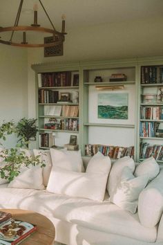 a living room filled with lots of white furniture and bookshelves full of books