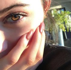 a close up of a person holding their hands to their face with the sun shining on them